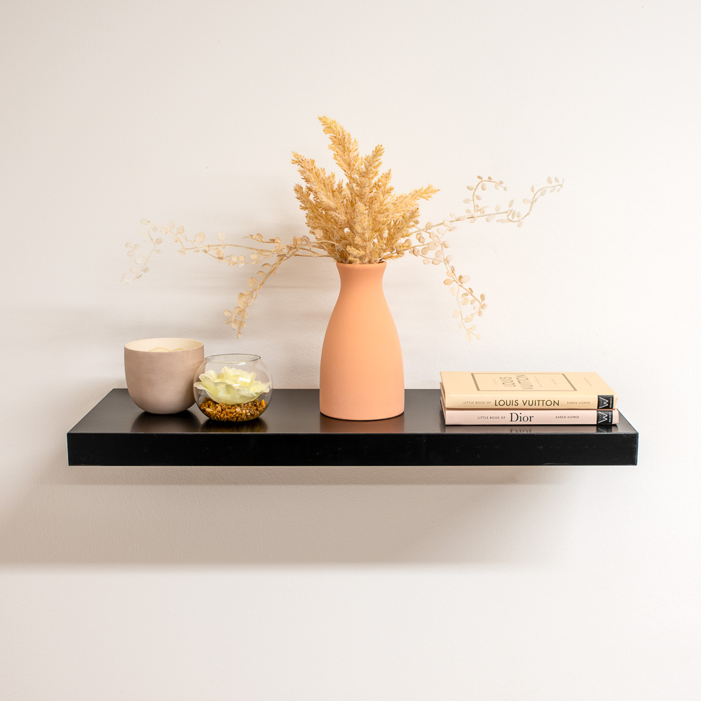 Black floating shelf with fake plant and books