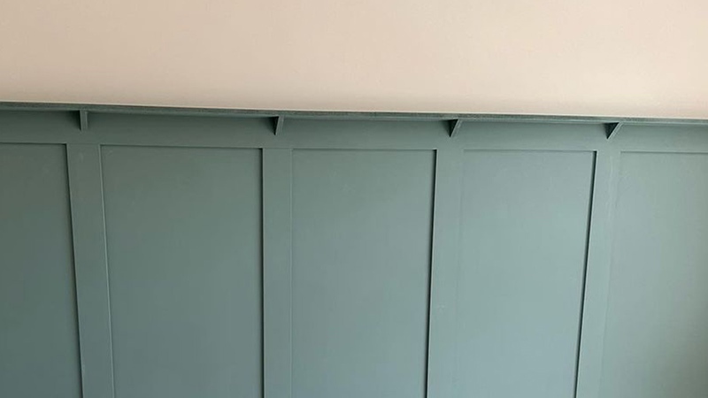 Picture shelf on green panelling